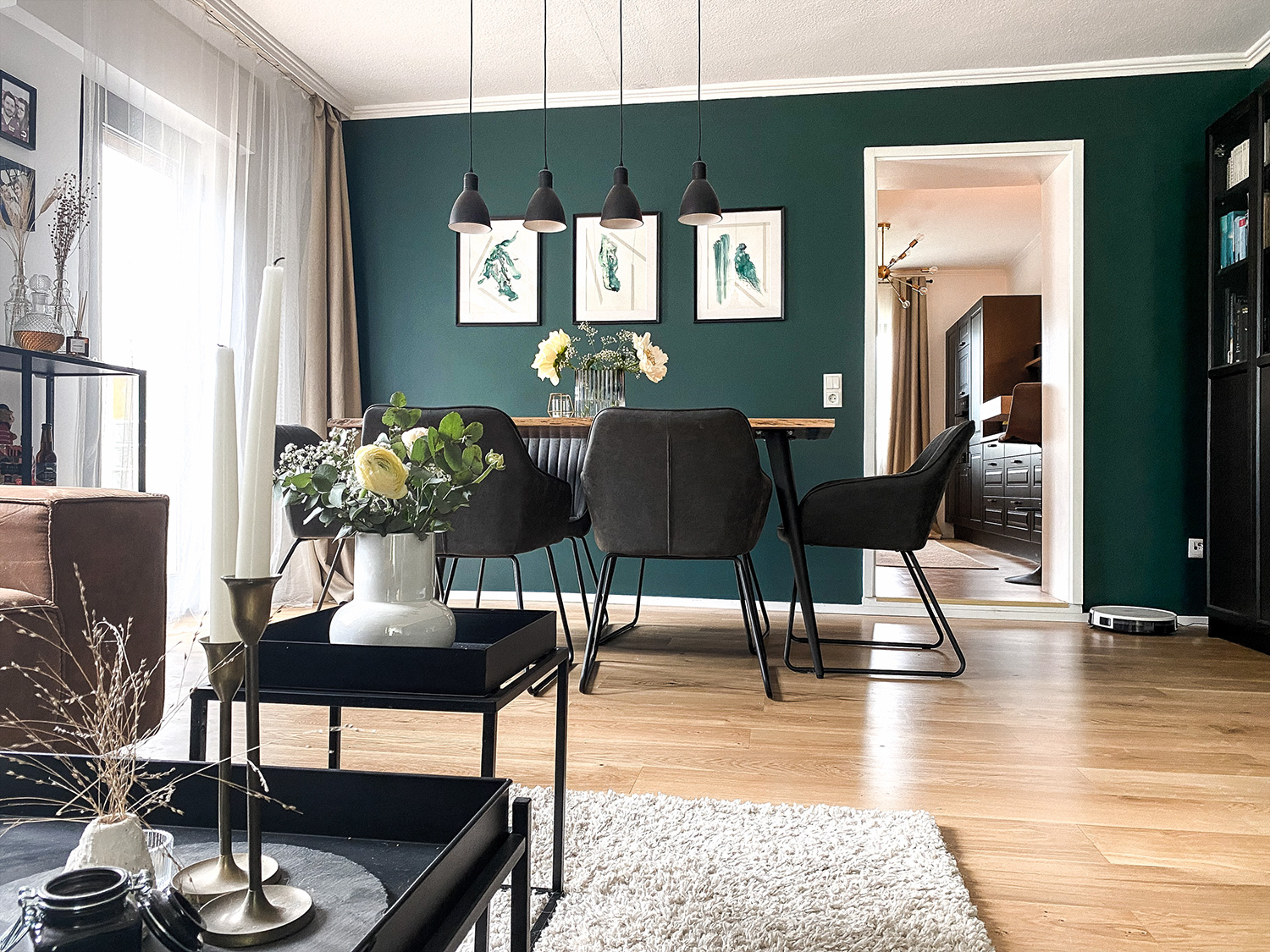 Three artworks by Rose Reichart titled Intuitive Abstracts featured in a spacious modern home with a boho interior touch. The framed paintings combine green fluid shapes and delicate lines with a lot of white space, making them pop on the bold green statement wall of the collector's contemporary living room.