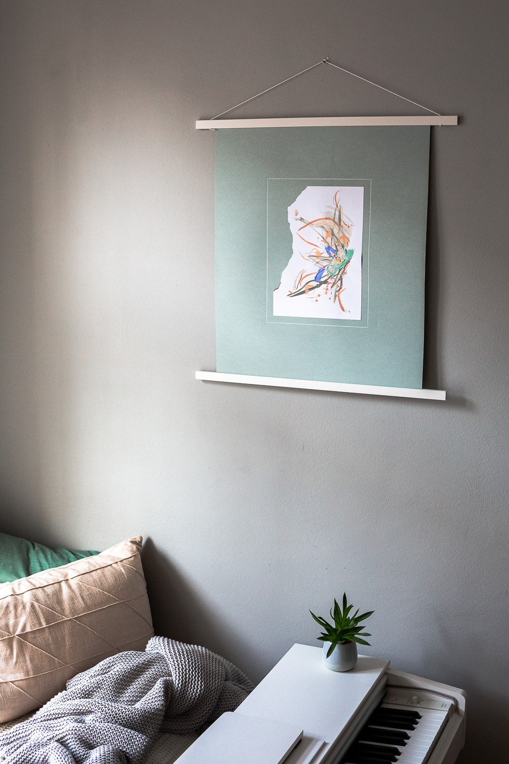 perseverance iii is an original abstract artwork by Rose Reichart. Here it is featured in a home with modern interior design in neutral shades. The intuitive painting is mounted on a mint colored paper and hangs on the wall with a white magnetic poster frame. Muted colors in tones of mint, peach, sage, beige and gray are present in the piece.