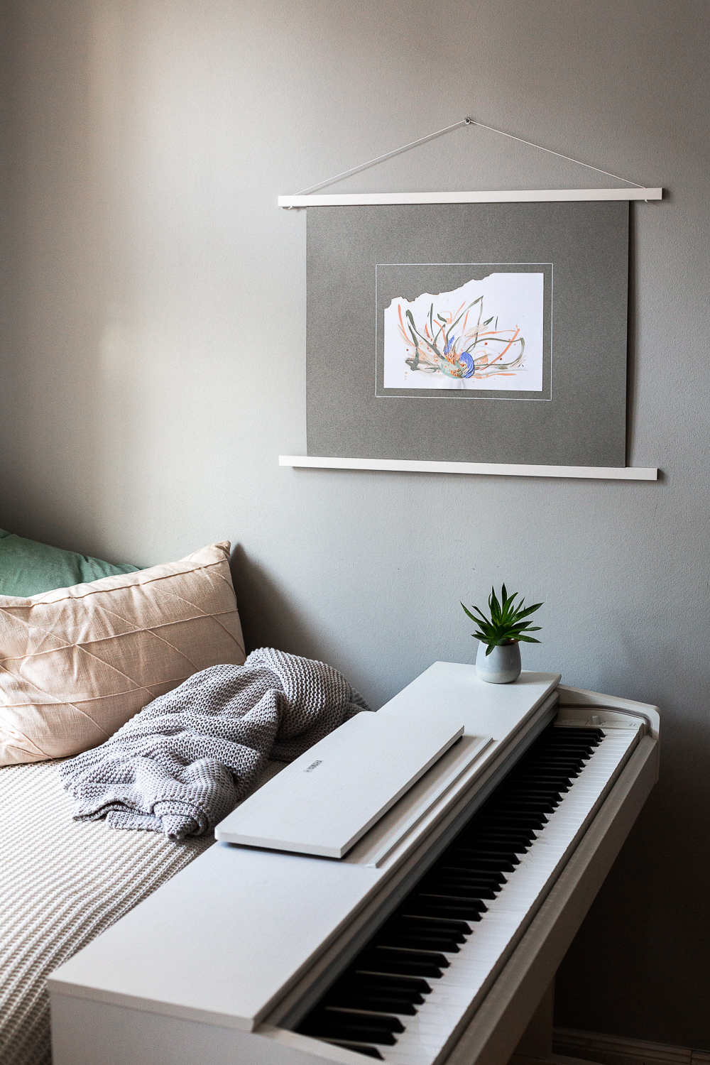 solidarity ii is an original abstract artwork by Rose Reichart. Here it is featured in a home with modern interior design in neutral shades. The intuitive painting is mounted on a gray colored paper and hangs on the wall with a white magnetic poster frame. Muted colors in tones of mint, peach, sage, beige and gray are present in the piece.