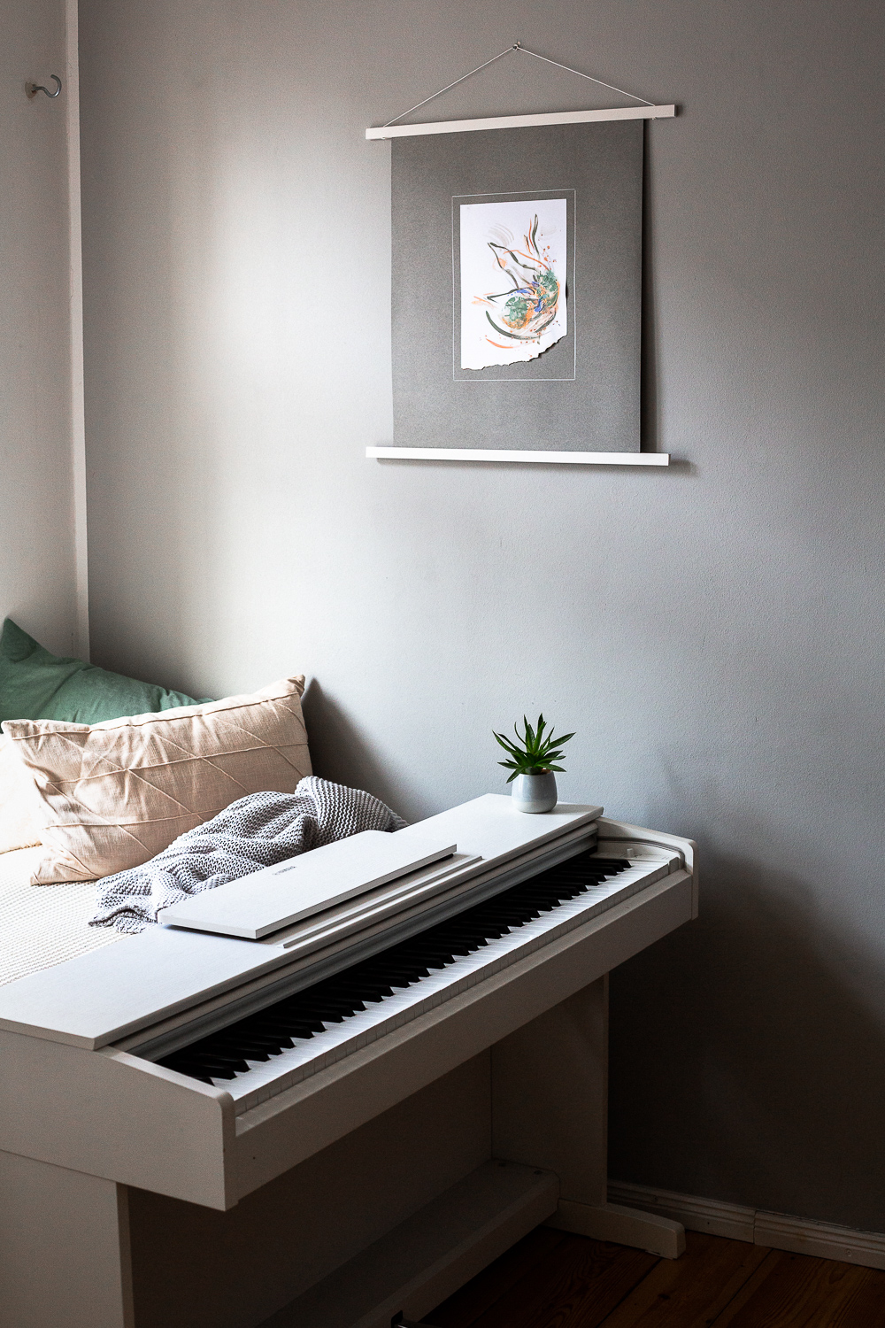 solidarity iii is an original abstract artwork by Rose Reichart. Here it is featured in a home with modern interior design in neutral shades. The intuitive painting is mounted on a gray colored paper and hangs on the wall with a white magnetic poster frame. Muted colors in tones of mint, peach, sage, beige and gray are present in the piece.